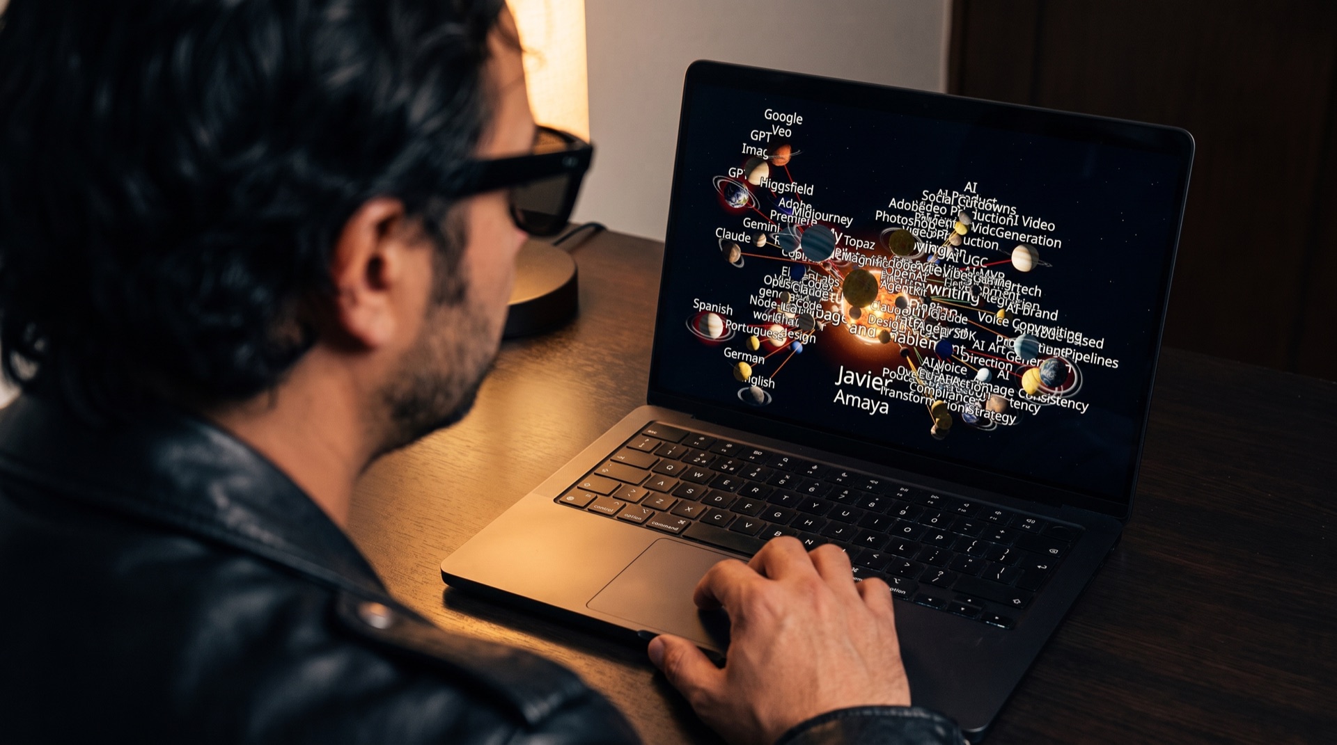 Javier Amaya from behind, in sunglasses and a black leather jacket, looking at the AI Graph on a black MacBook Pro.
